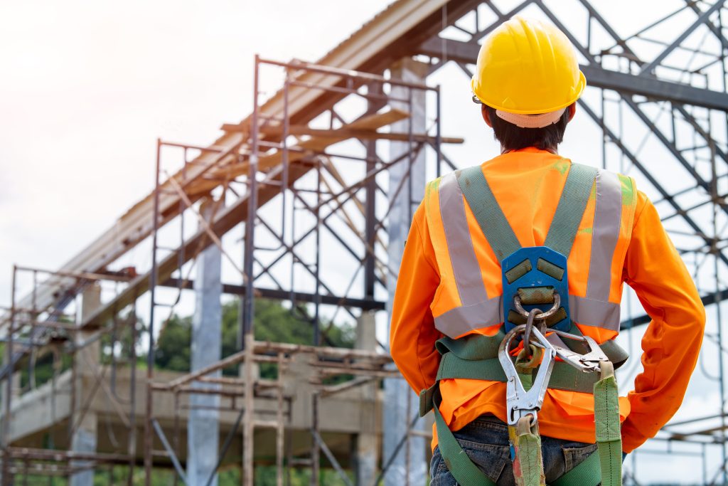 Construction worker wearing safety harness and safety line working at high place,Practices of occupational safety and health can use hazard controls and interventions to mitigate workplace hazards.